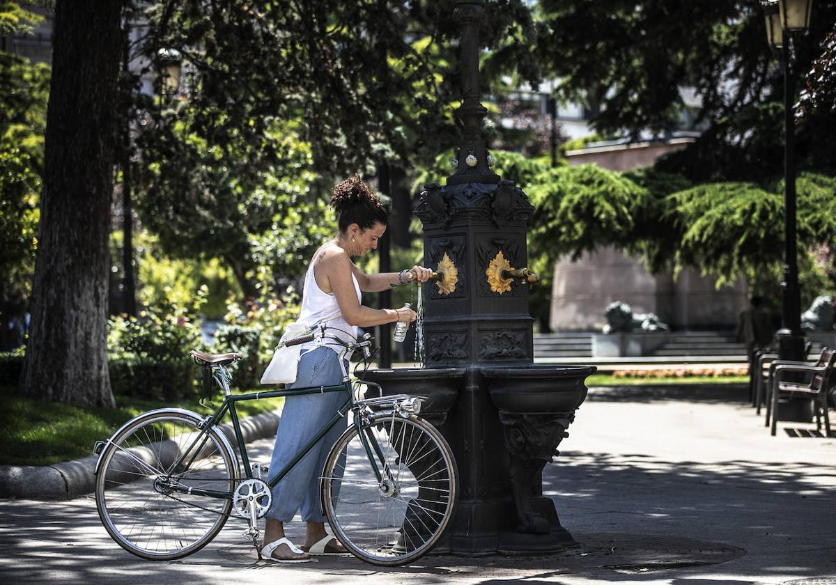 Mujer rellenando una botella de agua en una fuente.