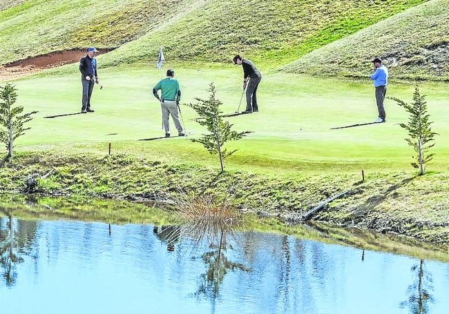 Jugadores practicando golf junto a la balsa del campo de Sojuela.