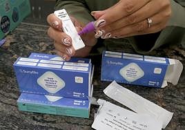 Una farmacéutica muestra un kit de test de covid y gripe.