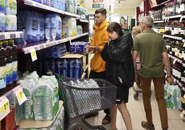 Clientes compran agua mineral en un supermercado.