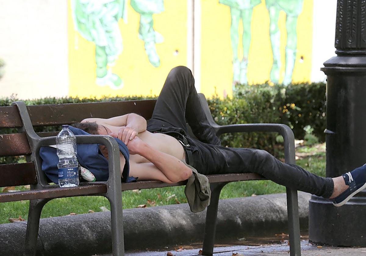 Un joven se tumba descamisado y con la botella de agua al lado, en un parque de Logroño.