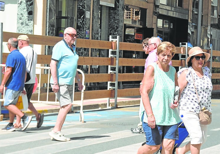 Imagen principal - Arriba peatones delante del vallado del encierro, en las dos de abajo feriantes de las atracciones. 