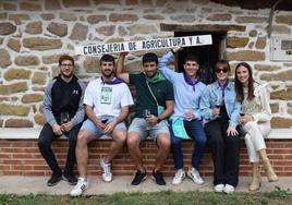 Un grupo de jóvenes bromea con un cartel de la Consejería de Agricultura en la puerta de una bodega de Alberite.