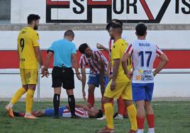 El colegiado se interesa por el estado de un jugador del Barbastro tendido sobre el césped.