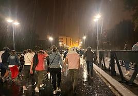 Numerosos logroñeses, por el puente de Hierro bajo una intensa lluvia