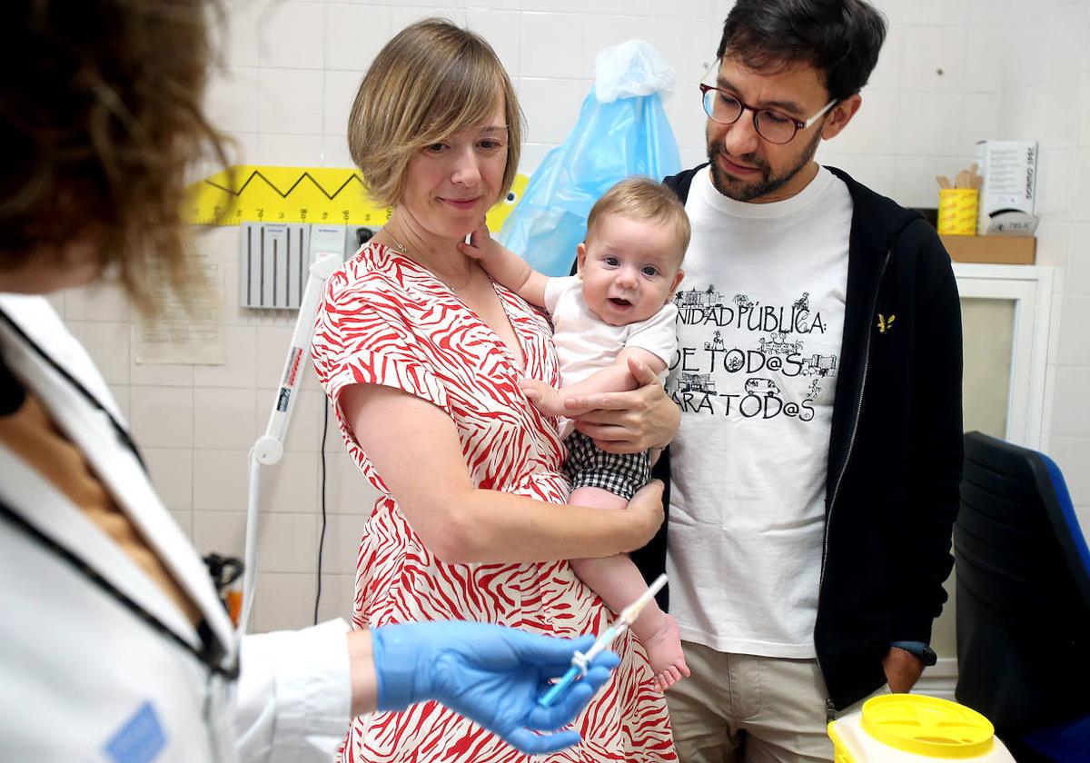 Noelia Jiménez y Rubén Carbonero sujetan a su hijo Martín mientras la enfermera prepara la dosis para inmunizarle frente a la bronquiolitis.