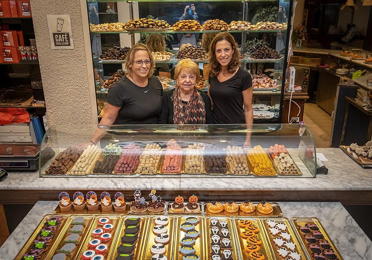 Carmen Cruz junto a sus hijas María Jesús y Susana posan junto a los huesos desanto y las pastas decoradas que hacen alusión a Halloween.