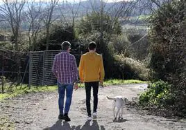 Óscar, junto a Pablo, y la perrita labrador Nala pasean en los jardines de la comunidad terapéutica de Proyecto Hombre.