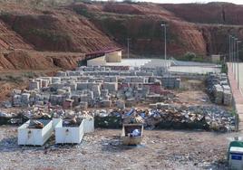 En primer plano, el punto limpio provisional en una finca municipal en Tambarría, con varios contenedore y zona de papel y cartón; al fondo, a unos metros, las nuevas instalaciones aún sin entrar en uso.