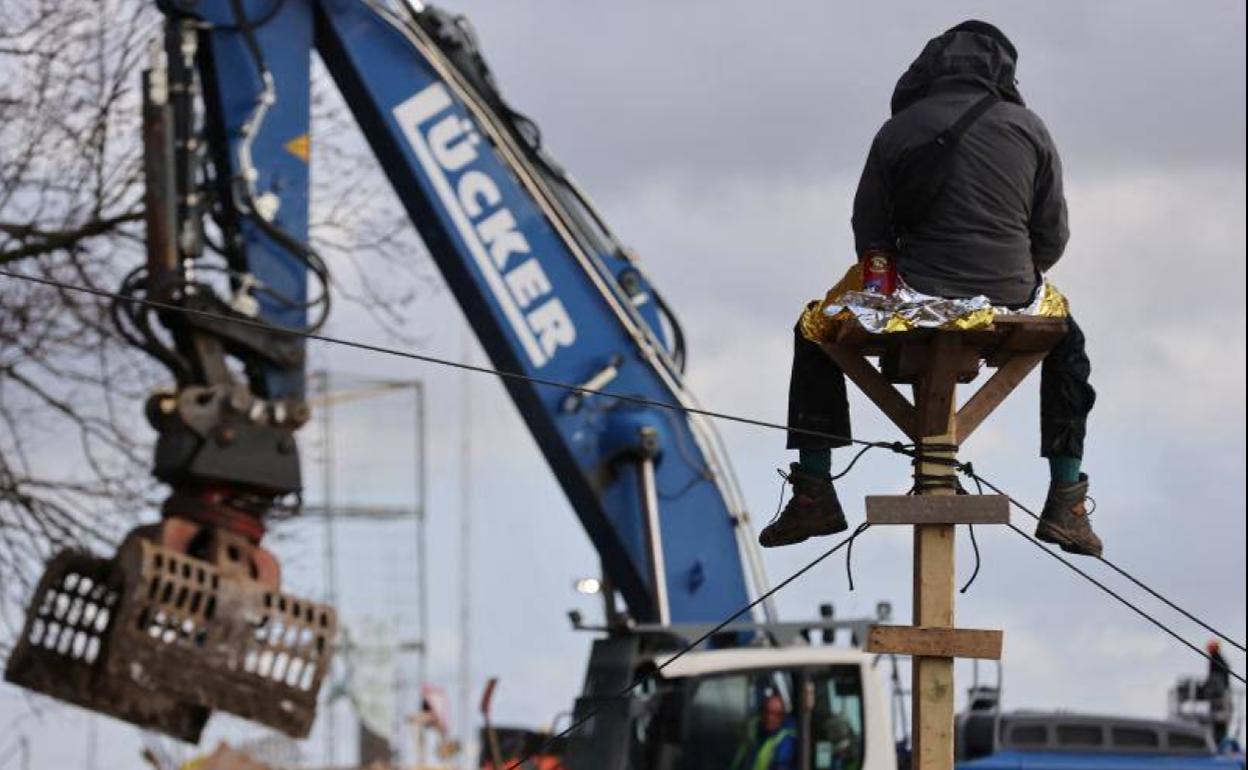 Un activista observa cómo una excavadora derriba una barricada instalada para obstaculizar el acceso de la Policía al pueblo de Lüzerath.