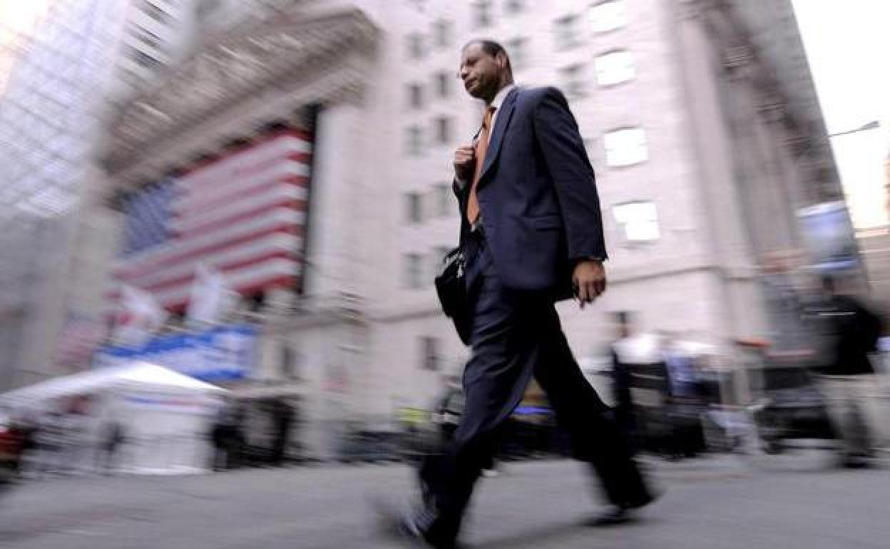 Un hombre camina junto a la fachada de Wall Streeet