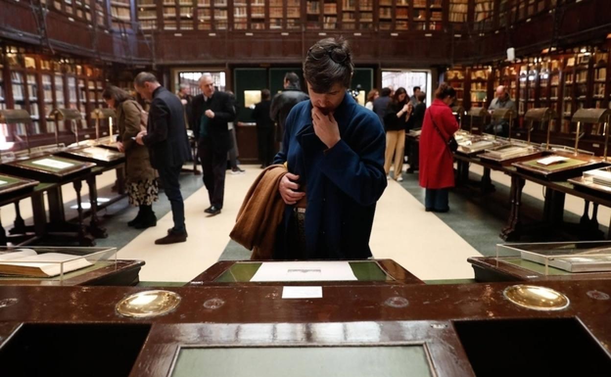 Espectadores contemplando los cuadros de Arruda en los pupitres de la biblioteca del Ateneo