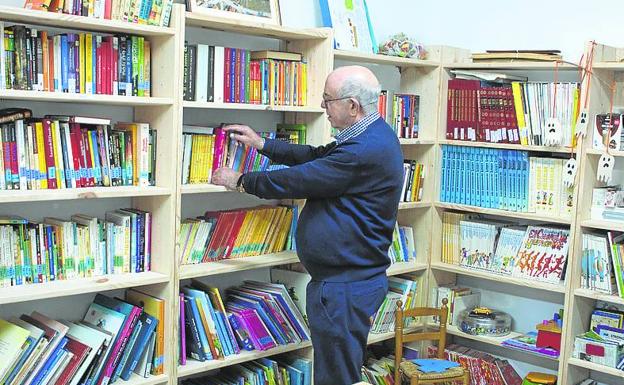 Isaac Palacios, alcalde cuando la biblioteca se puso en marcha, rebusca un ejemplar entre la estantería. 