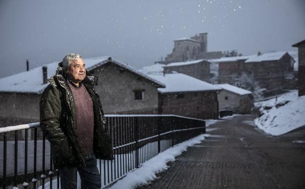 José Luis Merino Aldea, alcalde de Pinillos, posa con el pueblo al fondo, cubierto de nieve. 