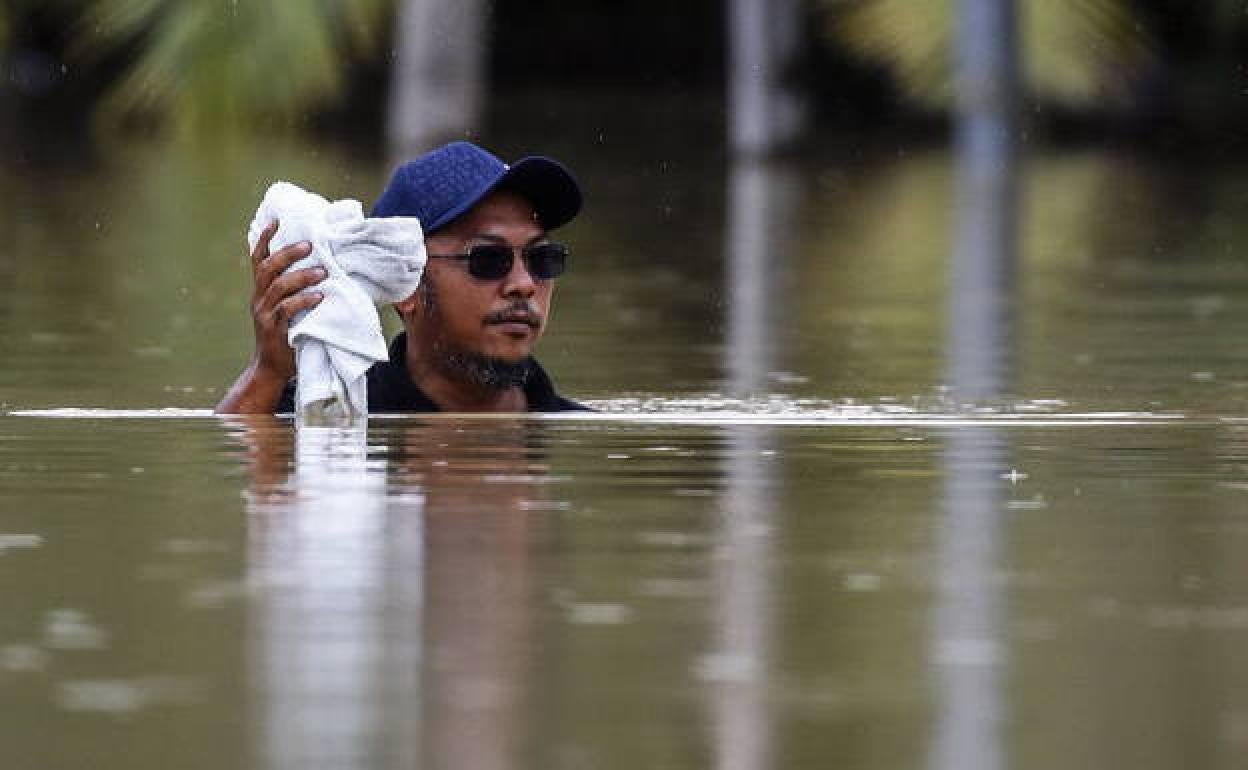 Un hombre camina en un área inundada mientras continúa la lluvia sobre Yong Peng, en Johor.