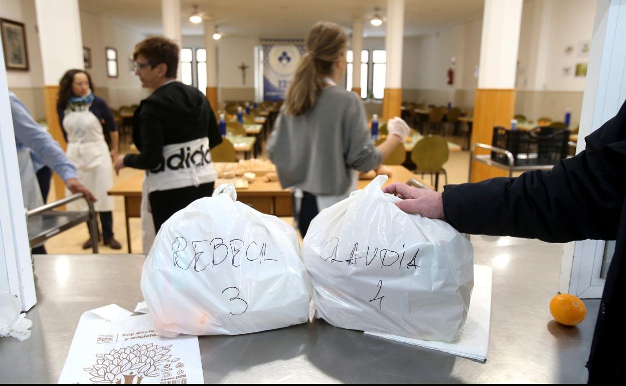 Voluntarios de la Cocina Económica, ayer mientras preparaban las bolsas con táperes de comida destinadas a algunas de las familias con niños que atiende la entidad. 