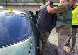 Uno de los detenidos es introducido en un coche por agentes de la Guardia Civil.