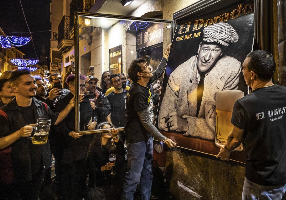 Juan y Alberto Martín Ramos descuelgan el célebre cartel que ha identificado el bar, en la calle Portales.