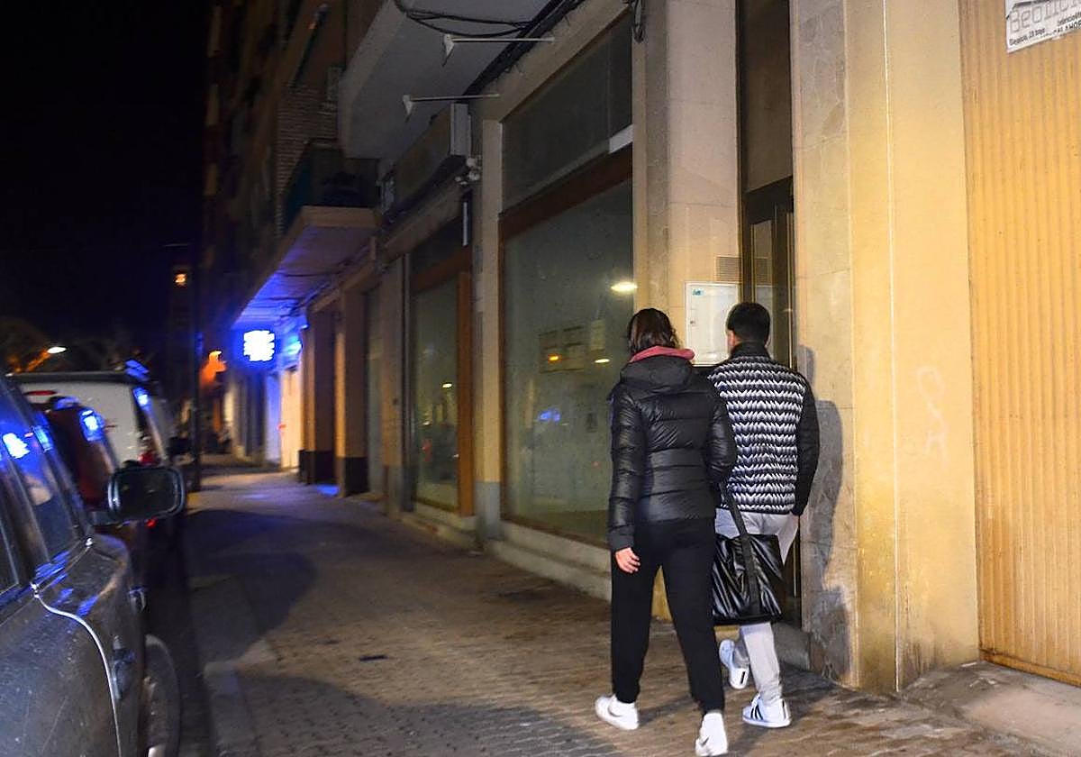 Una pareja pasa por delante del portal de la vivienda, en avenida de Valvanera, donde tuvo lugar la agresión.