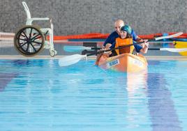 Una niña con discapacidad rema en las piscinas de Las Gaunas junto a su monitor.