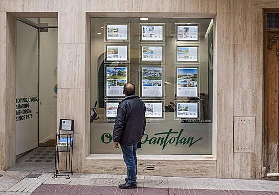 Un hombre mira el cartel de una inmobiliaria en Baleares.