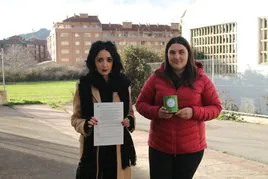 Cristina y Verónica, de Maullidos Solidarios, posan en el lugar del crimen con la denuncia presentada y una hucha para recaudar fondos.