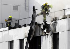 Los bomberos sofocan el incendio y, en detalle, el edificio, ayer.