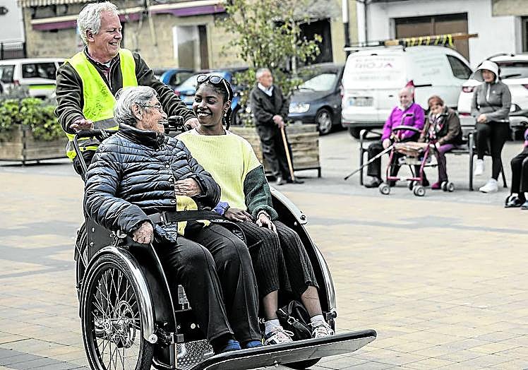 Andreas conduce a Ana María, acompañada de la voluntaria Melani, por la plaza de la Tela.