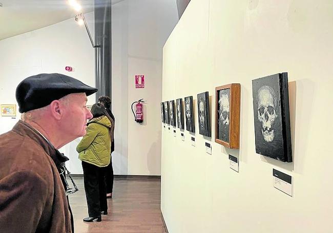 Un visitante a la muestra observa el cuadro de una calavera.