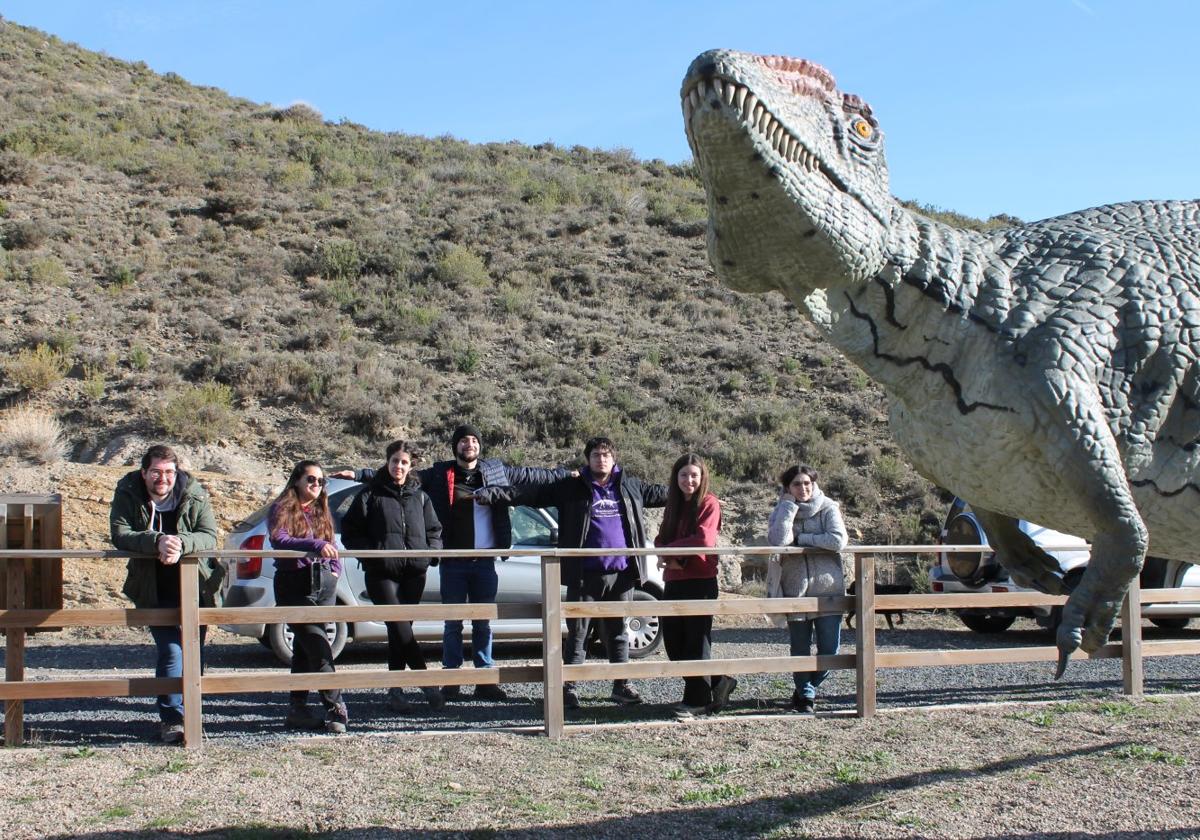 Organizadores del XXII EJIP junto a una réplica de un dinosaurio en al camino de acceso al yacimiento de Los Cayos de Cornago.