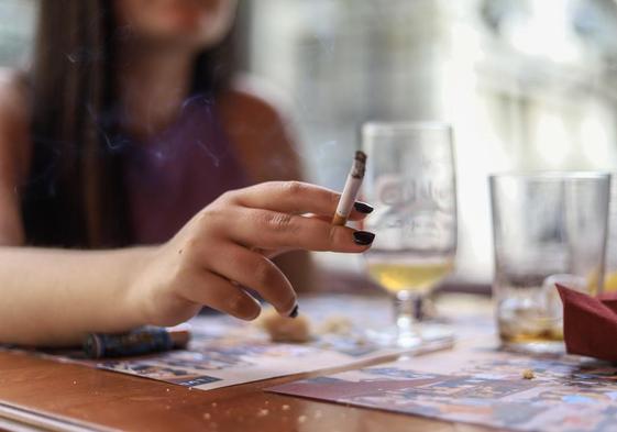 Una mujer fuma en la terraza de un bar.