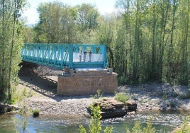 Tres personas conversan en el borde del puente-mirador de Arenzana con el río Najerilla a sus pies.