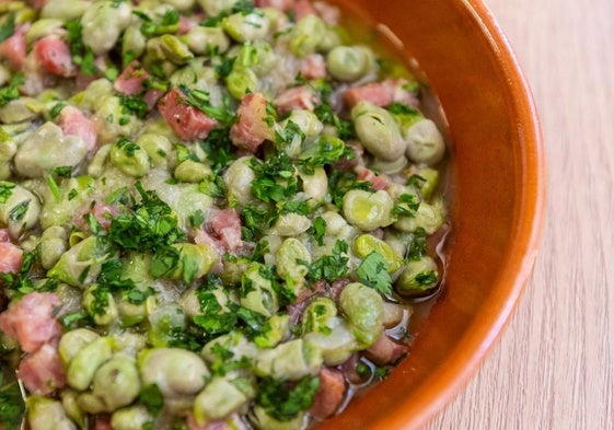 Un plato de barro con habas frescas con jamón.