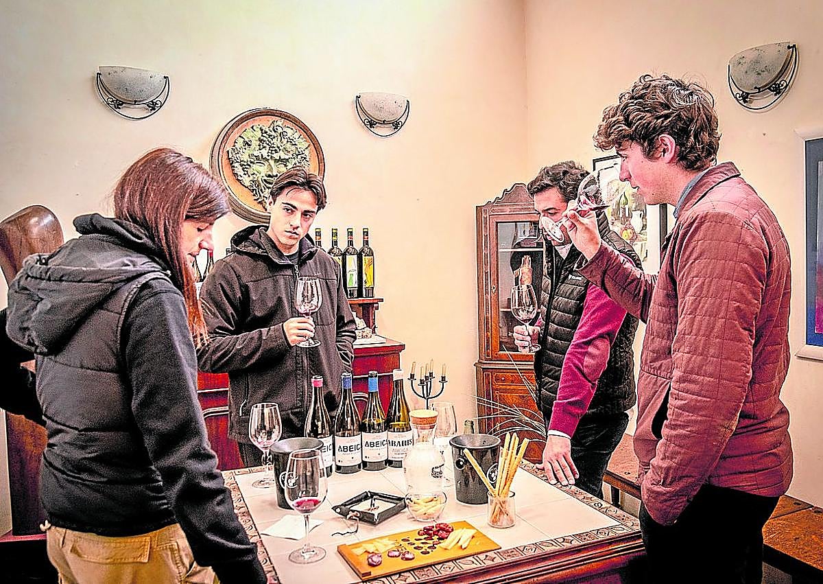 Imagen secundaria 1 - Arriba, Isabel en la zona de botellas. Abajo, David atiende una visita guiada y echa vino a una copa.