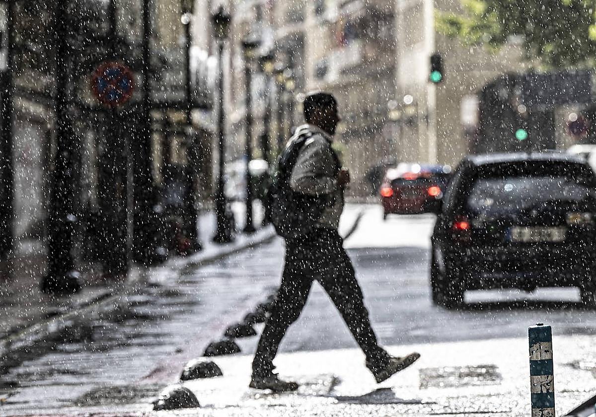 Un hombre pasea por el centro de Logroño entre lluvia y claros.