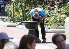 Un hombre se refresca en una fuente del Espolón.