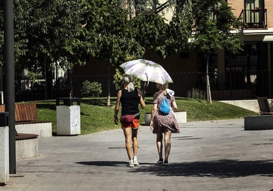 Dos mujeres se protegen del sol con un paraguas.