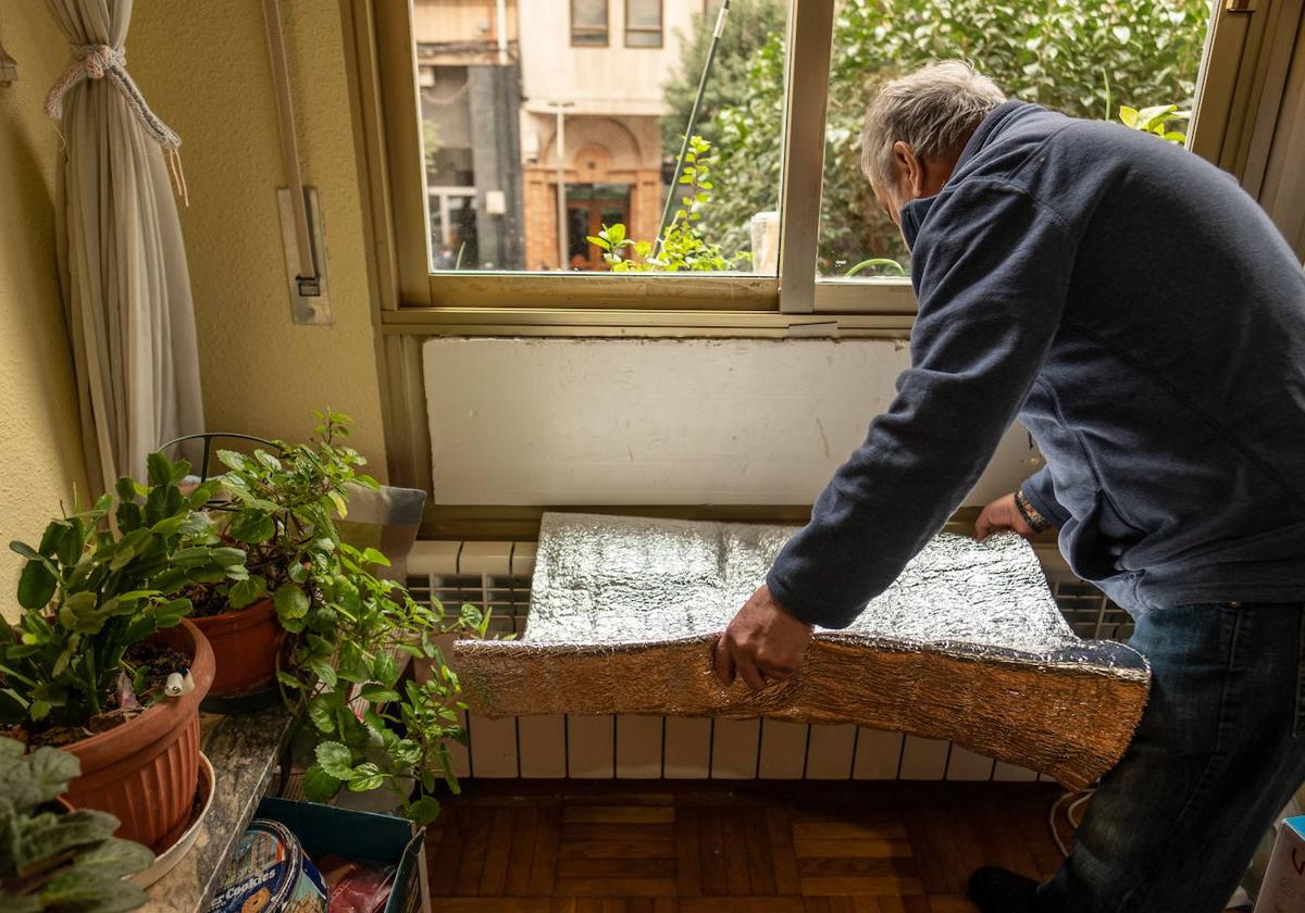 Imagen de archivo de un hombre que sufre pobreza energética trata de evitar que entre aire por las ventanas.