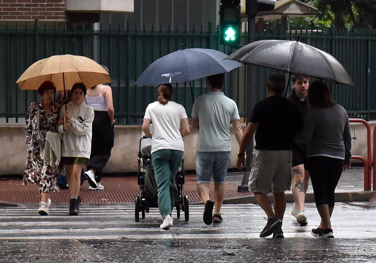 Varias personas se protegen de la lluvia en un día de tormenta en Logroño.