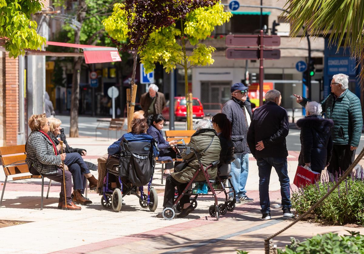 Personas mayores conversan sentadas al sol en un plazoleta de la capital riojana.