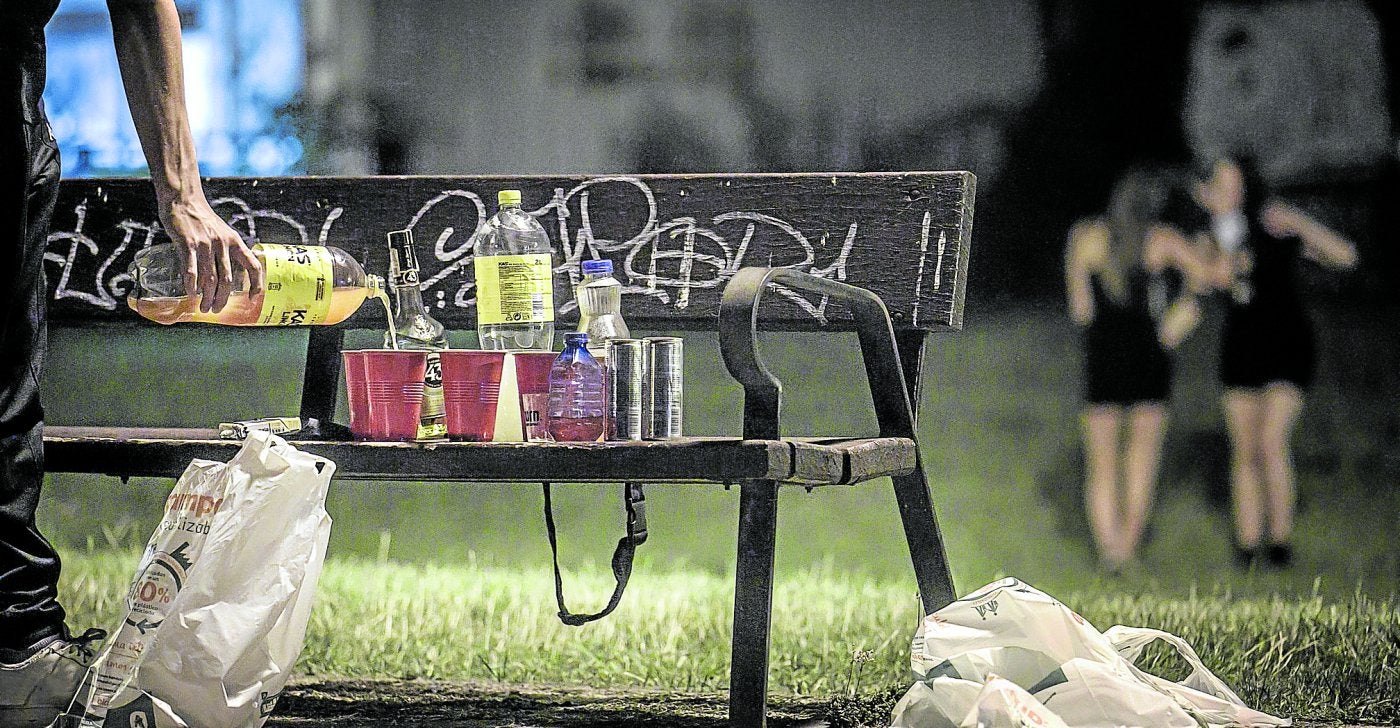 Un joven prepara las bebidas en un banco del parque del Ebro durante un botellón.