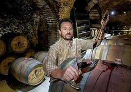 Javier Gutiérrez vigila el vino de una de sus barricas en el 'calao' donde las almacena, en pleno centro de Laguardia