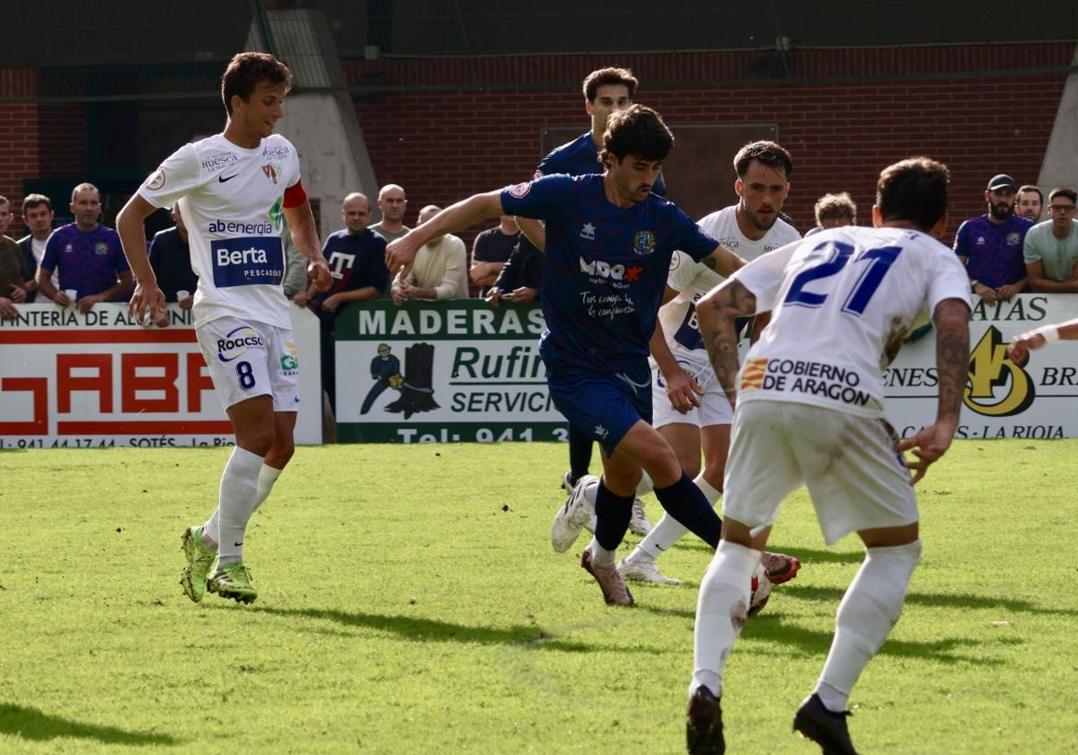 Rival correoso. Barace, con el balón, intenta zafarse del asedio de tres jugadores del Barbastro.