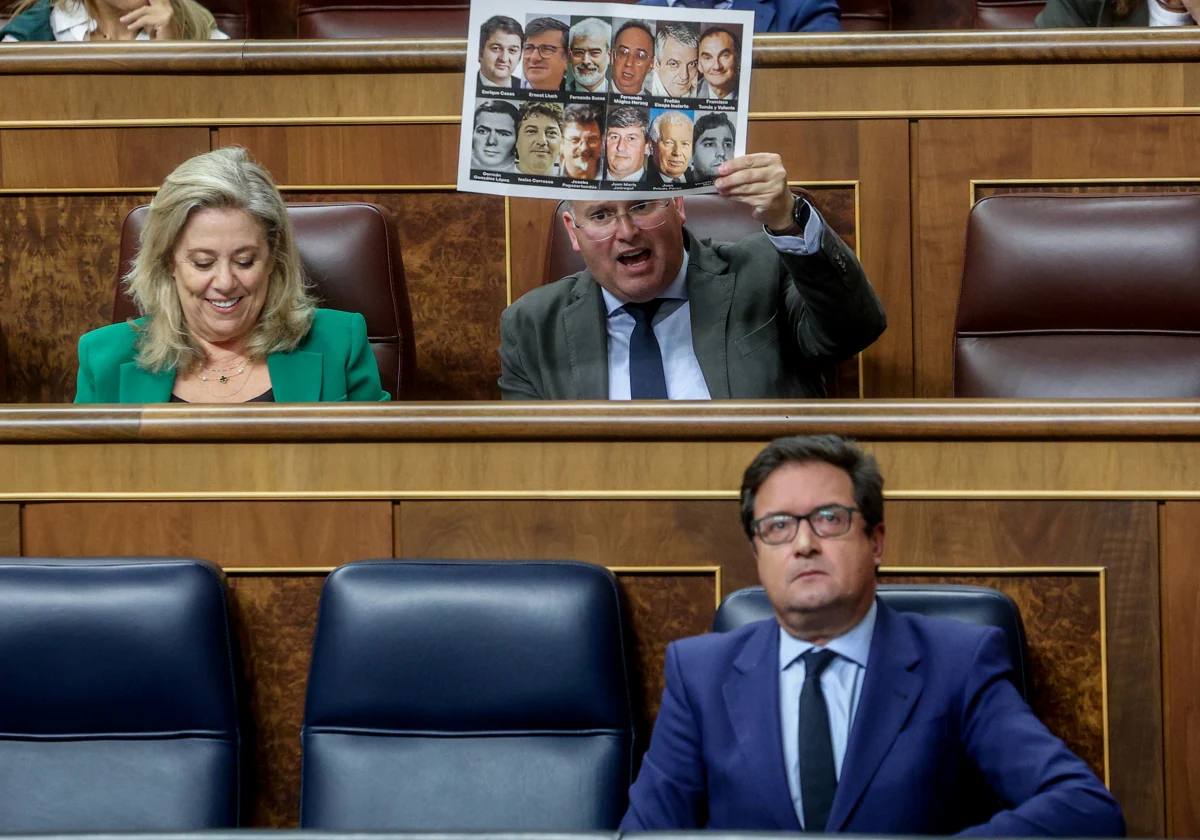 Tellado, detrá el ministro de Transición Digital, Óscar López, y junto a la diputada popular Macarena Montesinos, blande en el pleno un folio con las fotografías de socialistas asesinados por ETA 