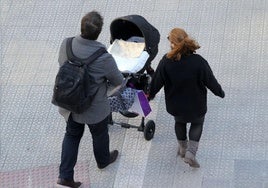 Dos padres pasean a su bebé en un carrito.