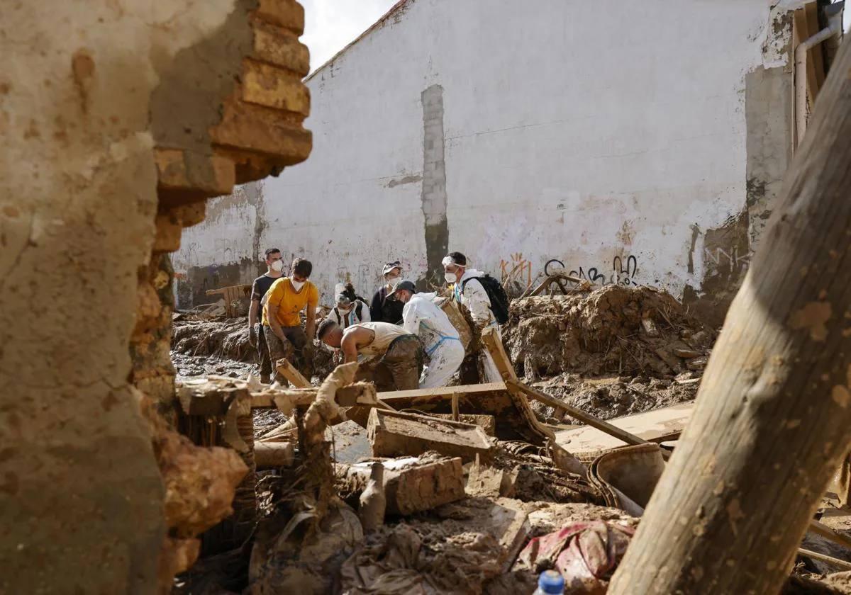 Voluntarios trabajan en la limpieza y desescombro de una calle de Masanasa, Valencia, este jueves.