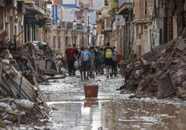 Voluntarios y afectados por la DANA, en una calle de Paiporta.