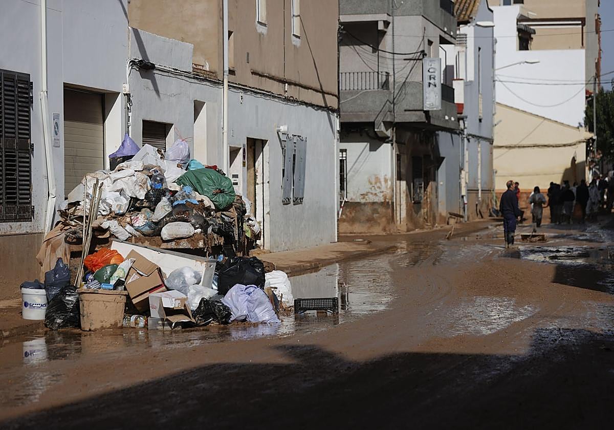 Enseres y bolsas de basura en una calle que seguía el pasado domingo cubierta de barro en Paiporta.