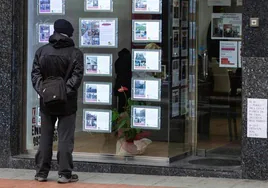 Un hombre mira anuncios de pisos en una inmobiliaria.