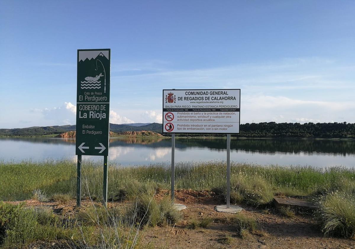 Embalse del Perdiguero, con un par de carteles identificativos, uno de ellos señalando la prohibición de introducir embarcaciones en el agua.